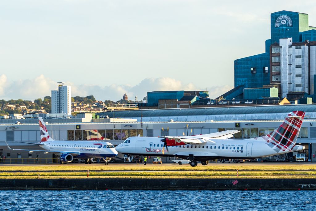 Airplanes parked at a city airport terminal, under a clear sky, capturing aviation activity.