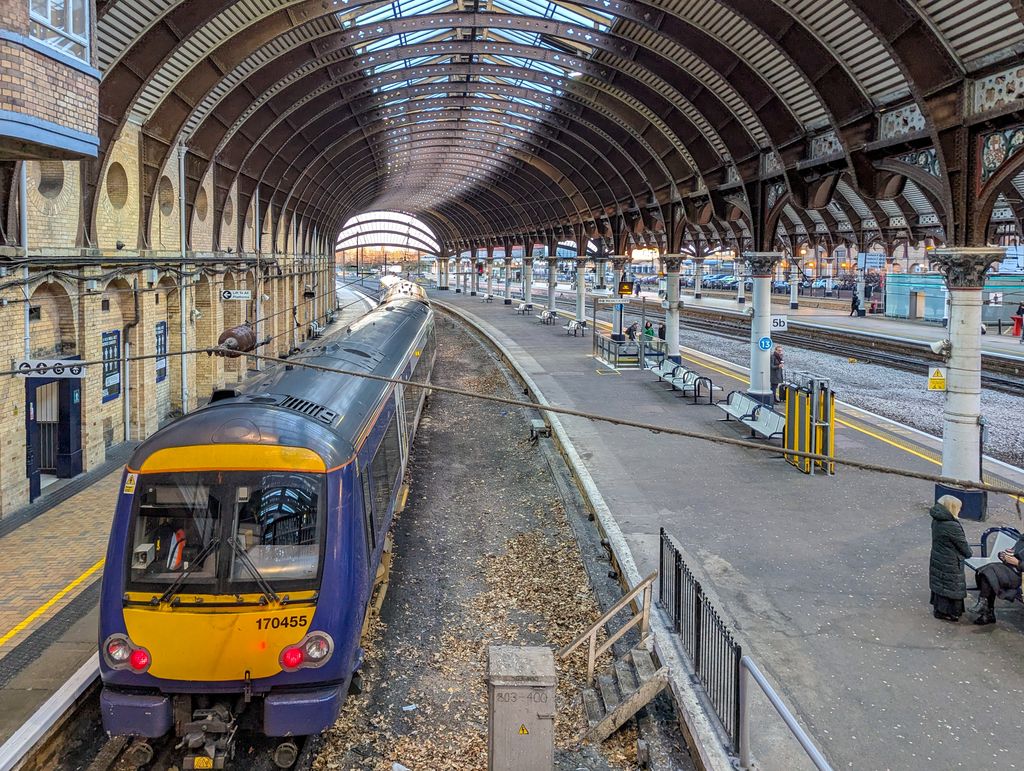 Panoramic view of York railway station showcasing the architecture, train, and platform in winter.