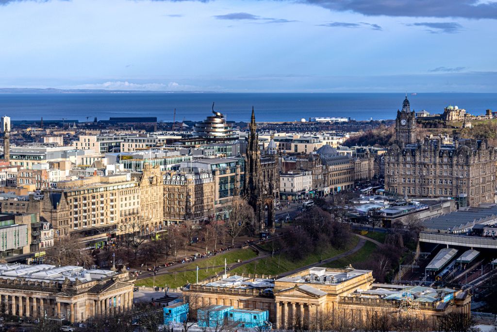 Stunning aerial view of Edinburgh with historic architecture and the coast in the distance.